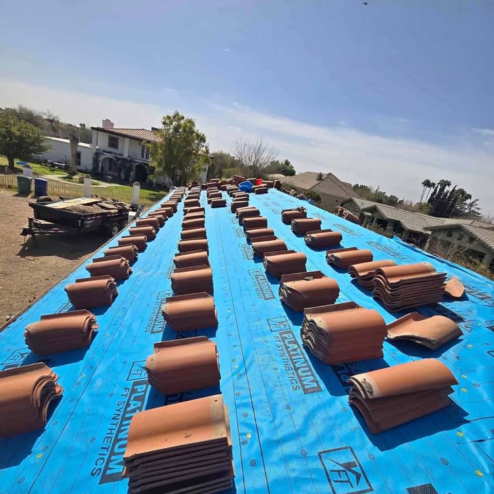 Stacks of barrel roof tiles staged on blue underlayment across a roof deck — Cristian House Remodeling LLC