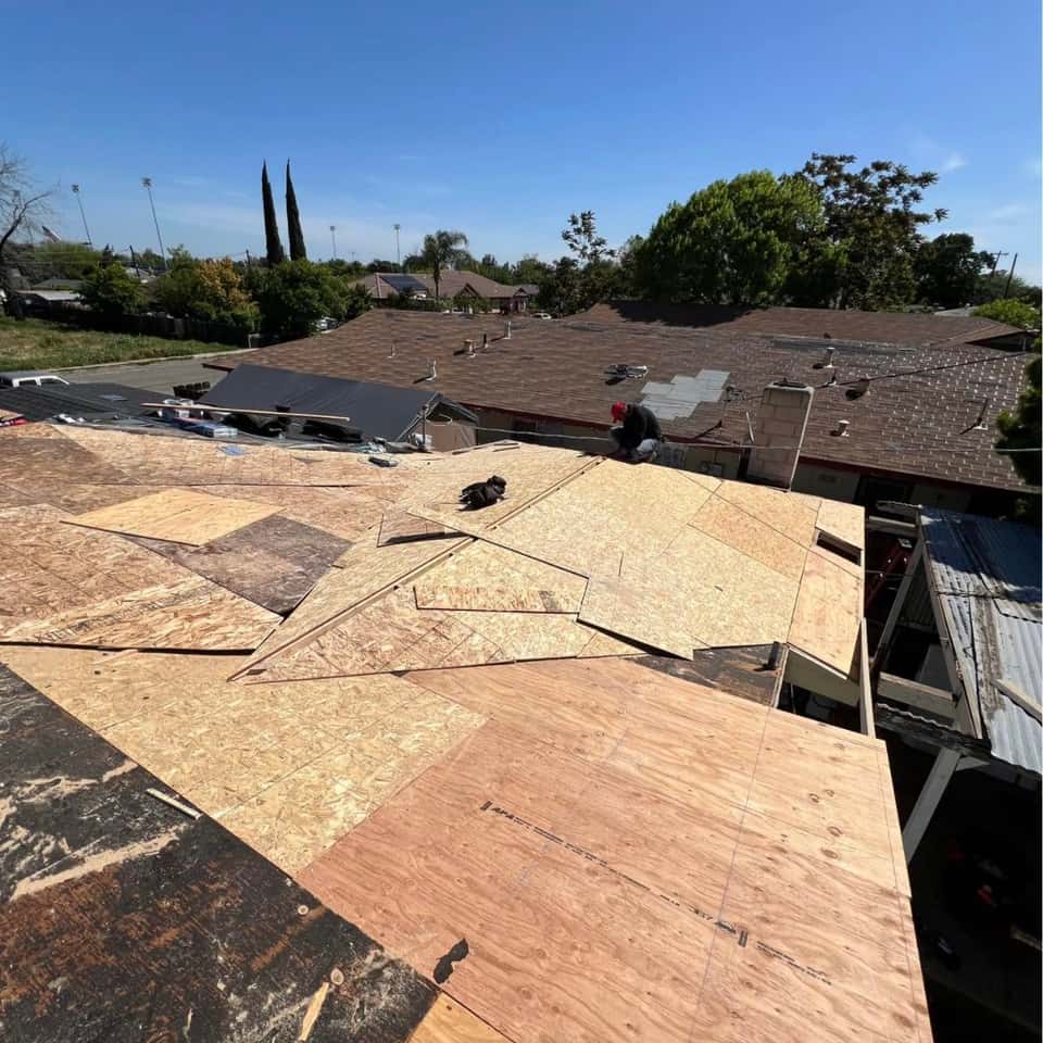 Roof mid tear-off with fresh plywood decking, seen from above — Cristian House Remodeling LLC