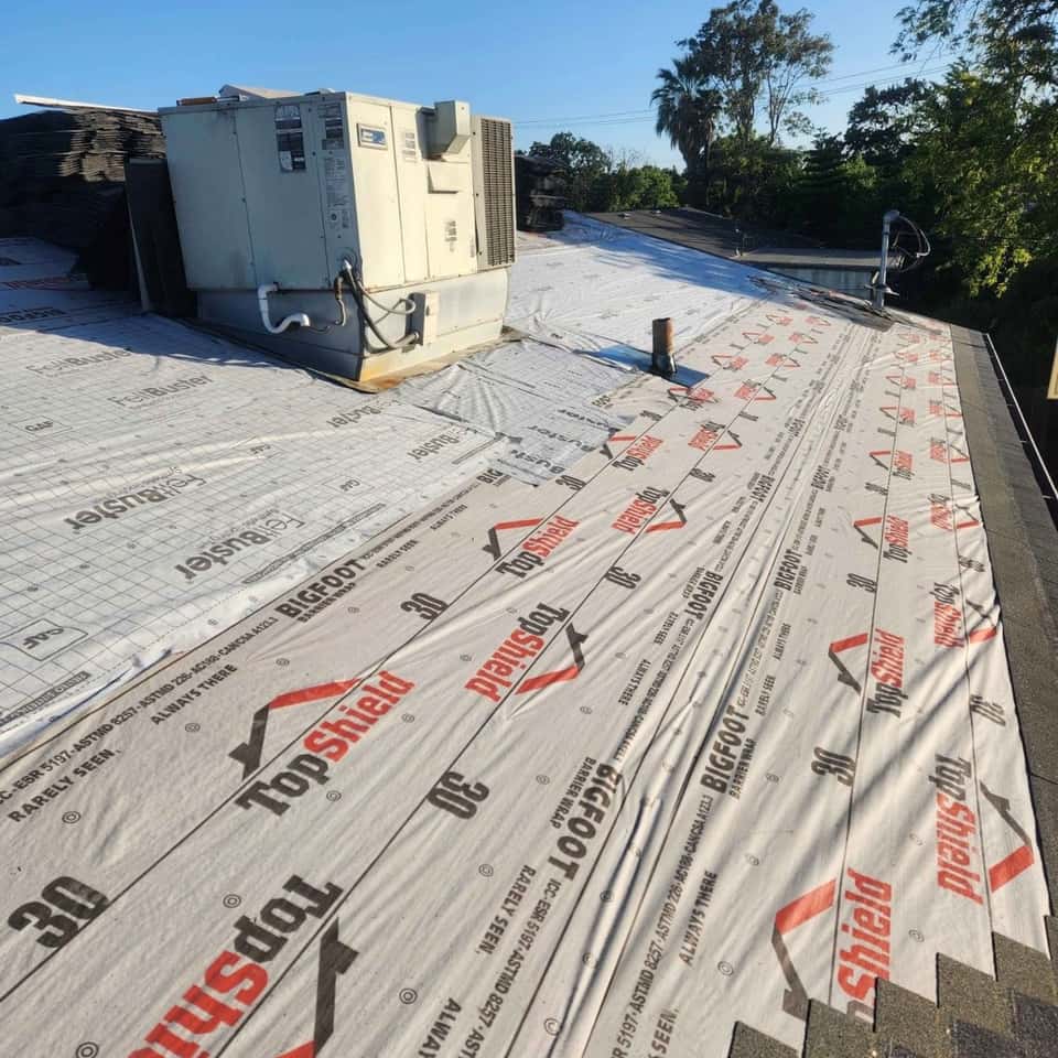 Synthetic roof underlayment being rolled out across a roof deck — Cristian House Remodeling LLC