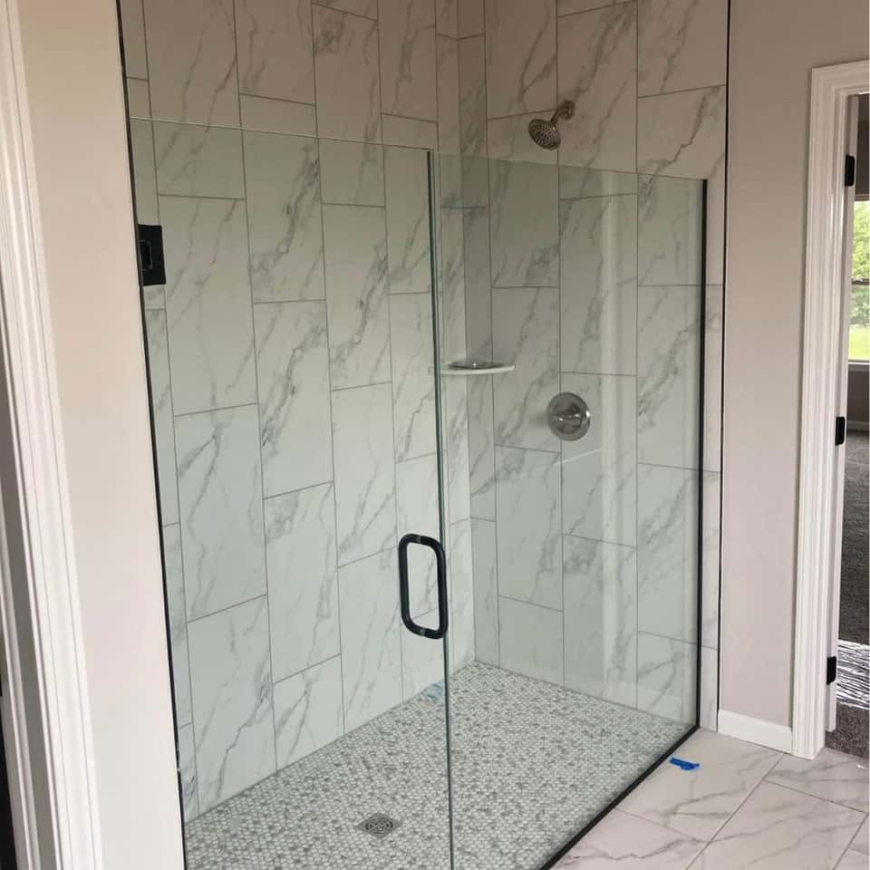 Finished marble-tile shower with a frameless glass enclosure — Cristian House Remodeling LLC