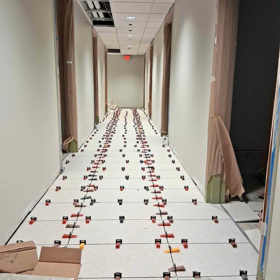Large-format corridor floor tile mid-set with levelling clips — Cristian House Remodeling LLC