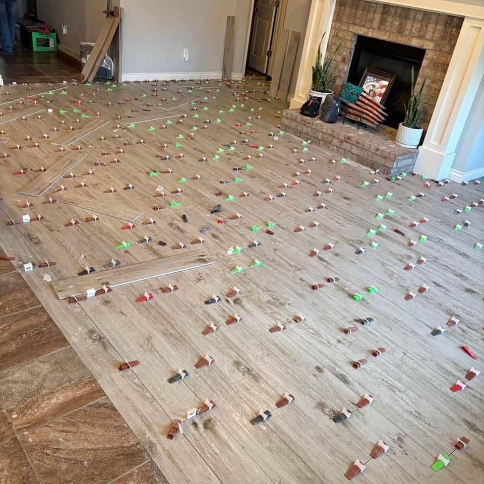Wood-look plank tile floor mid-set with levelling clips in front of a fireplace — Cristian House Remodeling LLC