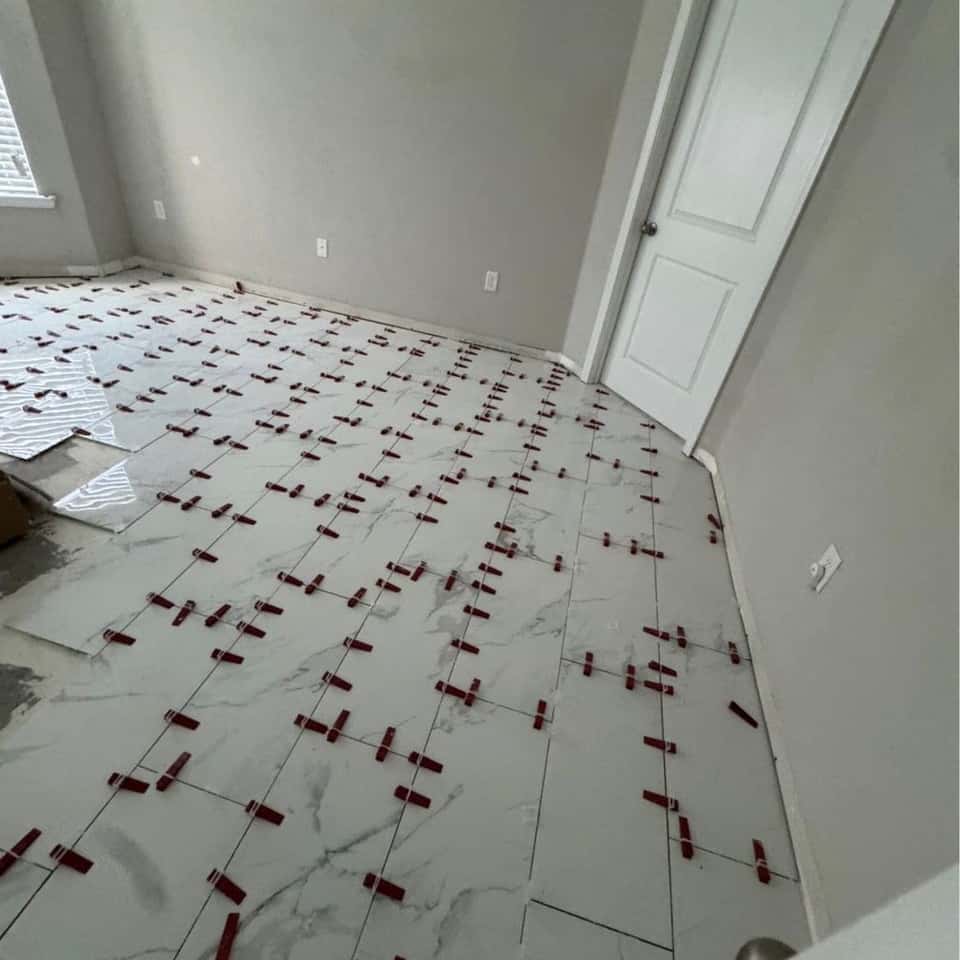 Floor tile mid-set with levelling clips in a room with new doors — Cristian House Remodeling LLC