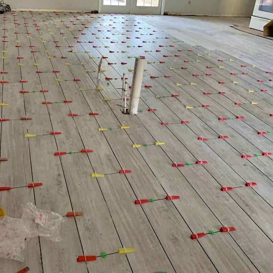 Wood-look plank tile floor mid-set in a bright room with windows — Cristian House Remodeling LLC