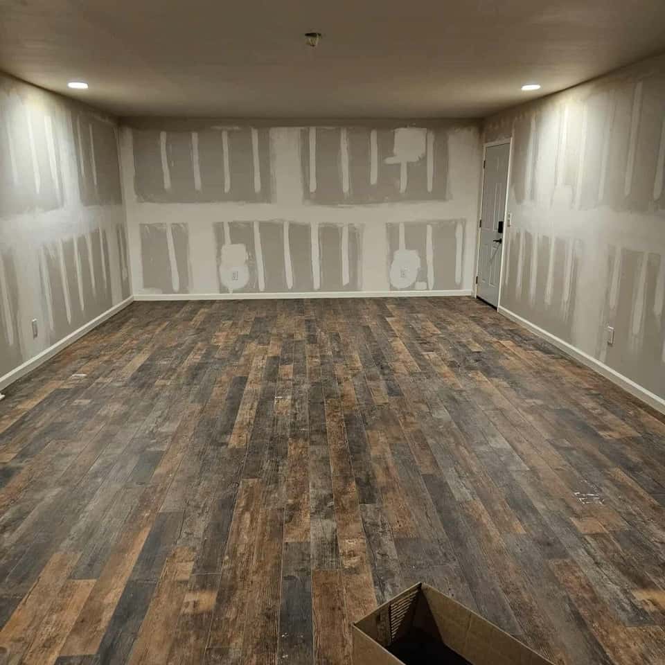 Room mid-remodel: new plank floor laid, drywall taped, outlets roughed in — Cristian House Remodeling LLC
