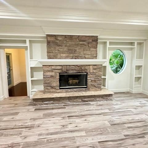 Living room with a stone fireplace, built-ins and a new wood-look floor — Cristian House Remodeling LLC